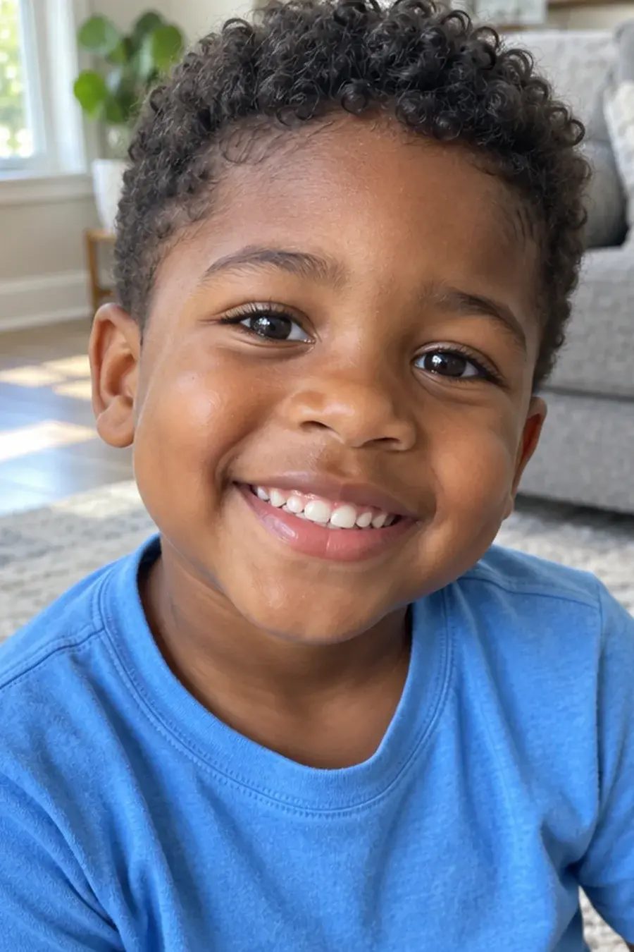 Photo of Kai, a smiling boy with short curls in a blue T-shirt